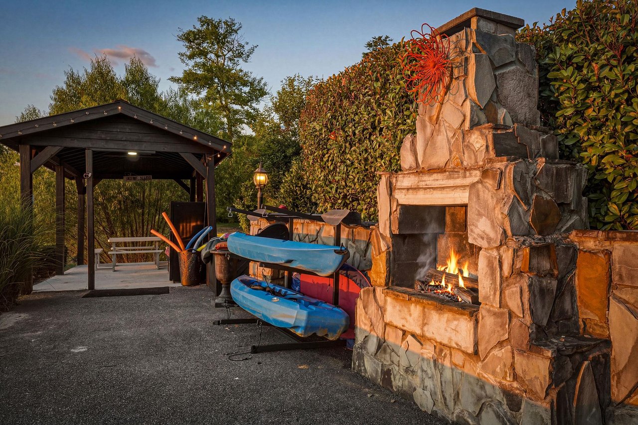 Outdoor living area featuring a stone fireplace,, and kayaks ready for your next adventure on the water.