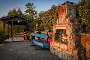 Outdoor living area featuring a stone fireplace,, and kayaks ready for your next adventure on the water.