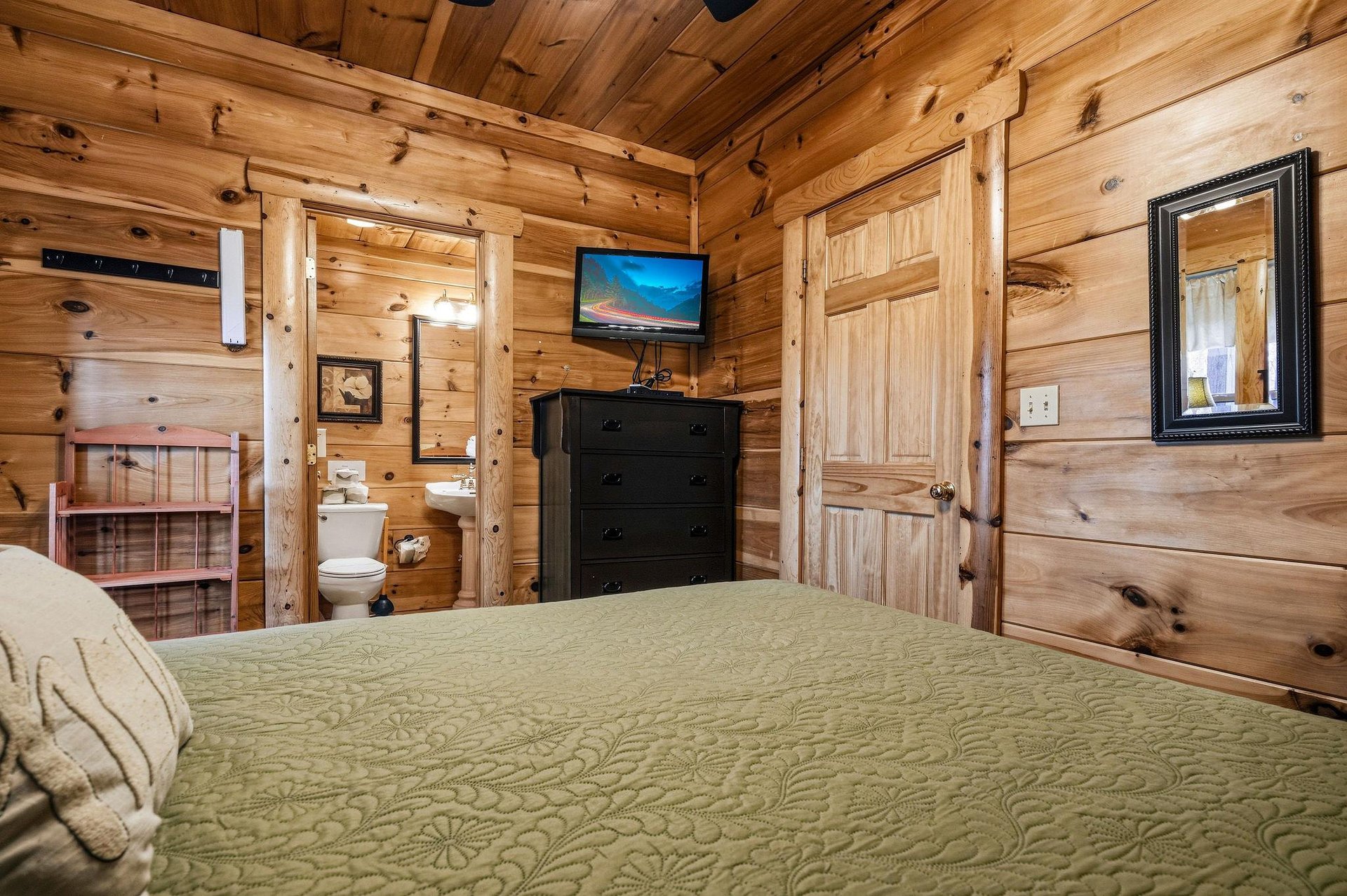 Cozy up in this rustic log bedroom where warm wood surrounds you, complete with your own TV and private bathroom for ultimate comfort.