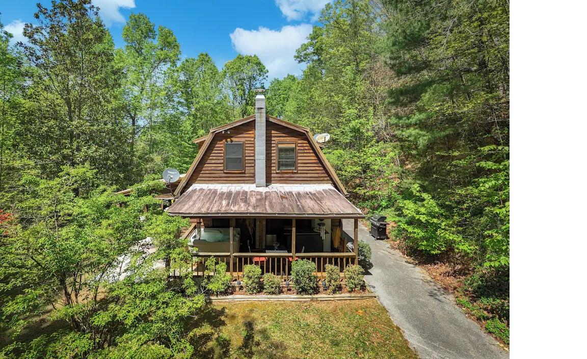 Charming log cabin nestled among towering trees, featuring a welcoming covered porch and peaceful forest setting for the perfect mountain retreat.