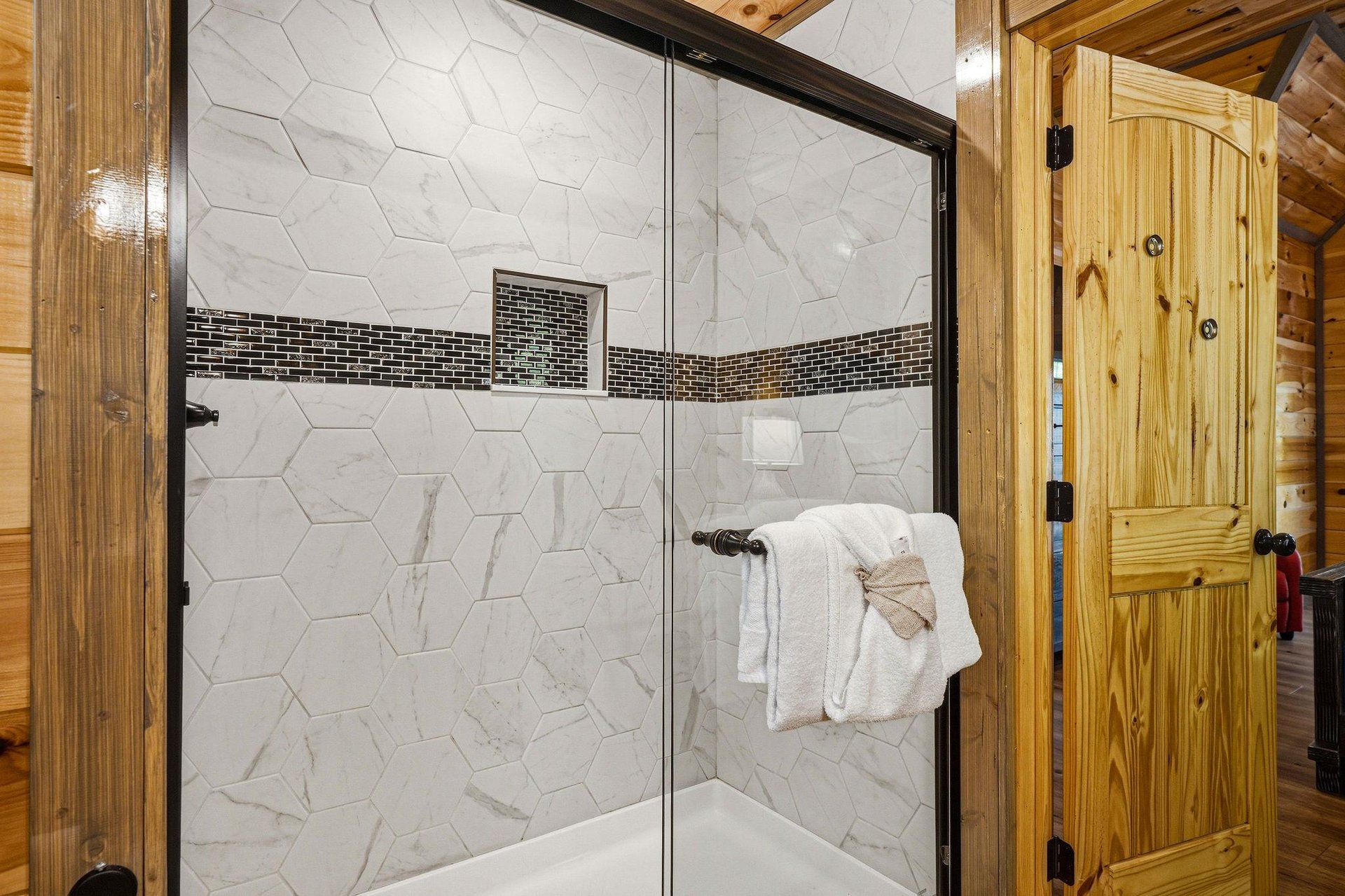 Step into your private marbletiled shower with elegant hexagonal design and rustic wood accents that create the perfect blend of luxury and cabin charm.