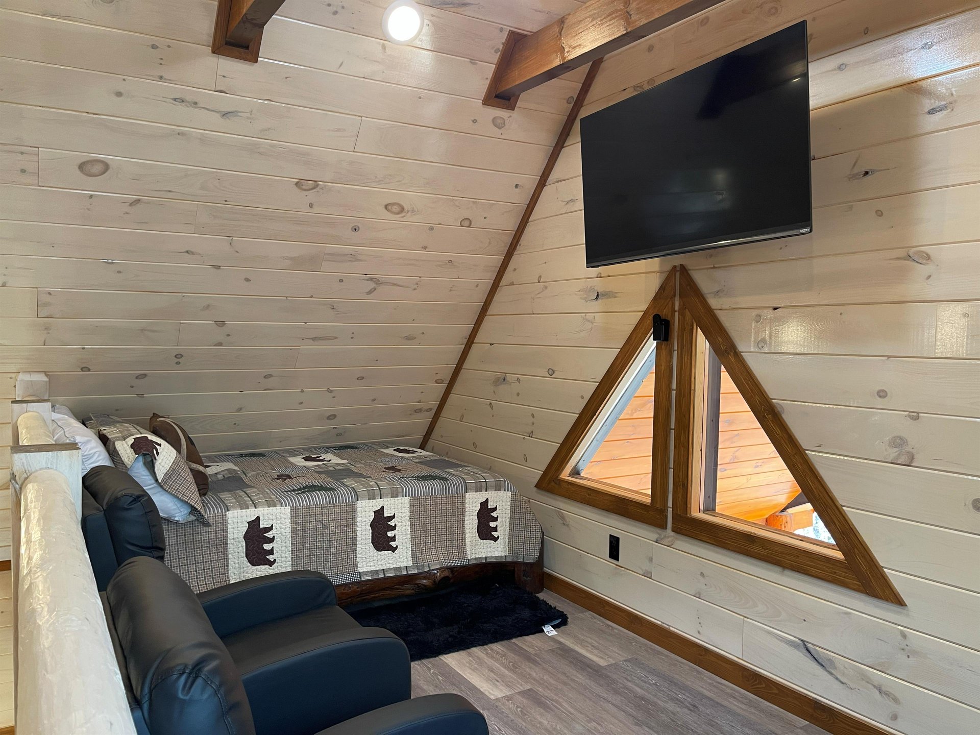 Cozy up in your private loft bedroom with rustic wood walls, a wallmounted TV for movie nights, and unique triangular windows.