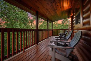 Unwind on your private covered deck as sunset paints the sky, surrounded by lush forest canopy and comfortable seating for peaceful evenings.