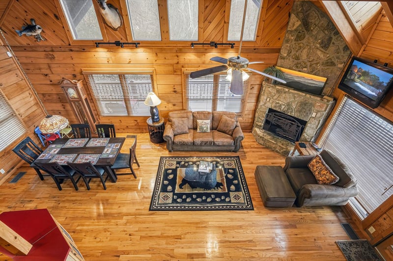 Relax in your spacious cabin living room with soaring ceilings, stone fireplace, and cozy seating perfect for mountain getaway evenings.