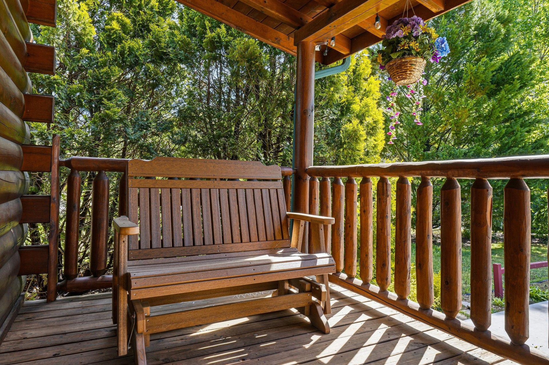 Relax on your private wooden deck with comfortable seating, surrounded by lush greenery and colorful hanging flowers for peaceful moments outdoors.