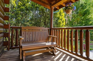 Relax on your private wooden deck with comfortable seating, surrounded by lush greenery and colorful hanging flowers for peaceful moments outdoors.