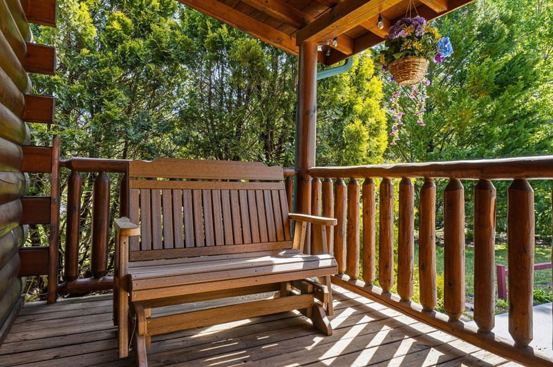 Relax on your private wooden deck with comfortable seating, surrounded by lush greenery and colorful hanging flowers for peaceful moments outdoors.