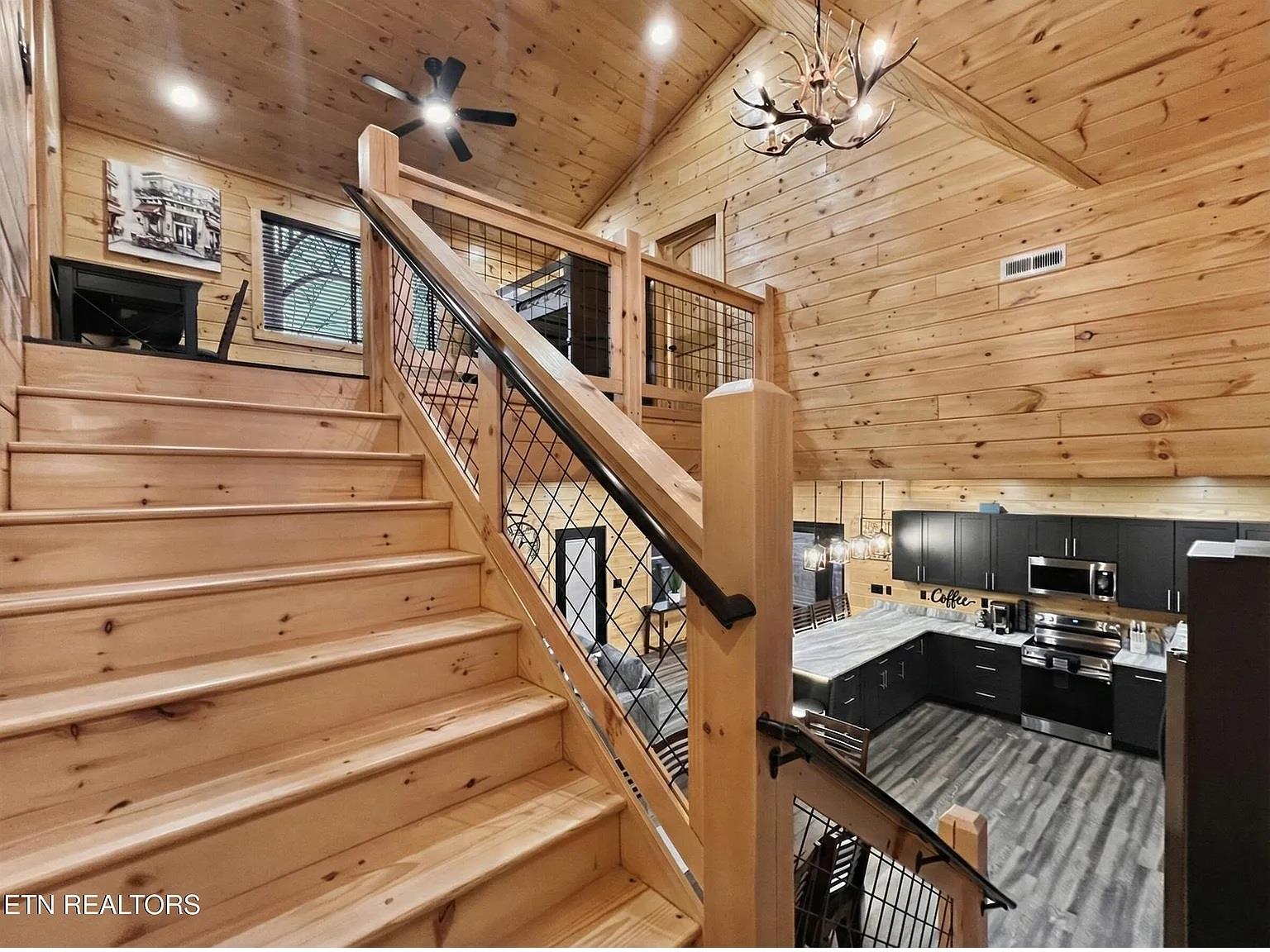 Your rustic retreat features stunning woodcrafted stairs leading to loft spaces, with modern kitchen below for memorable mountain getaway cooking.