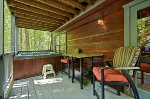 Relax on your private screened porch with a soothing hot tub, cozy seating, and tranquil forest views—your perfect retreat after a day of adventure.