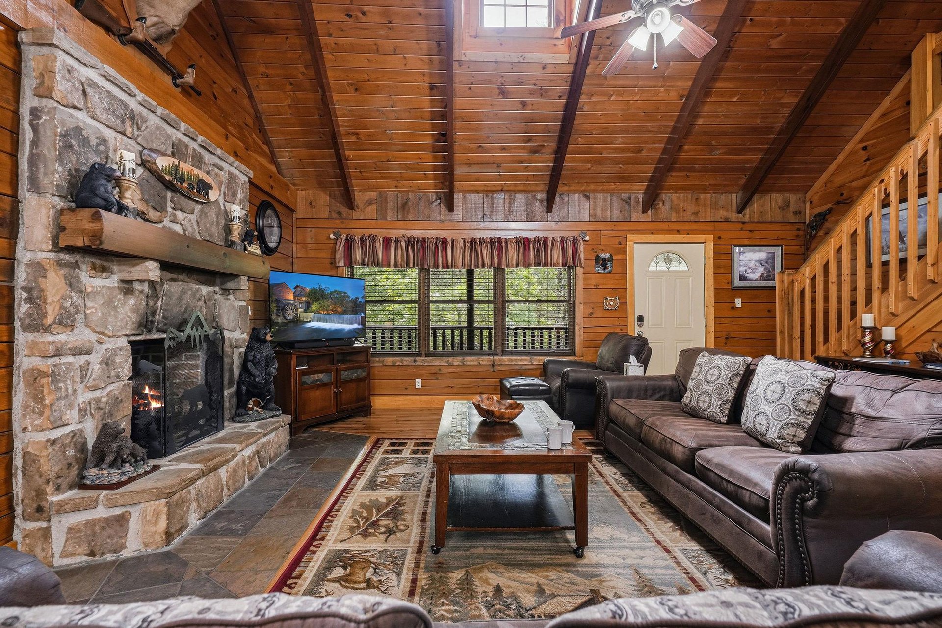 Sink into plush leather sofas by the crackling stone fireplace, where warm wood tones and vaulted ceilings create your cozy mountain retreat.