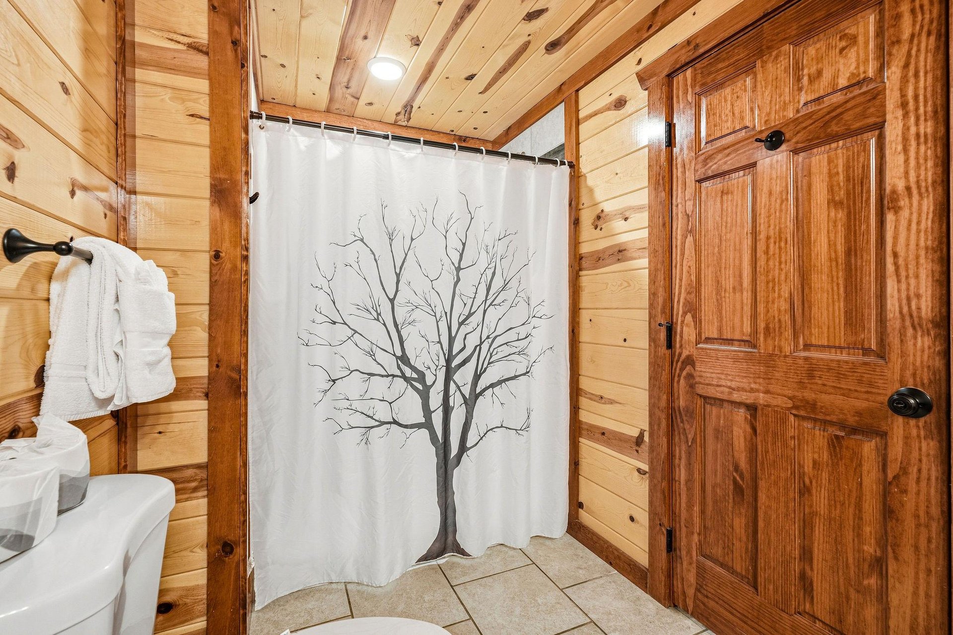 Refresh in your cozy cabin bathroom featuring warm wood paneling, fluffy towels, and natureinspired details.