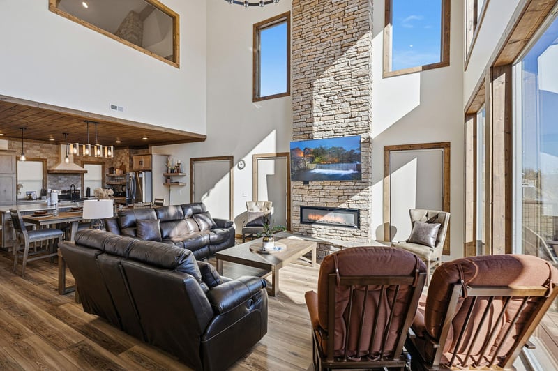 Unwind in your spacious living area featuring leather seating, a stunning stone fireplace, and floortoceiling windows that flood the space with natural light.