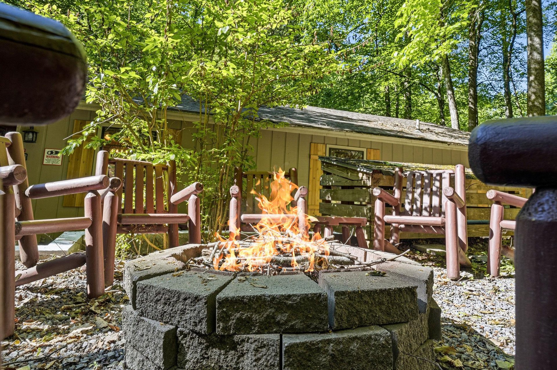 Private forested retreat offering a stone fire pit surrounded by rustic wooden benches—your own peaceful spot to gather under the trees.