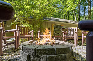 Private forested retreat offering a stone fire pit surrounded by rustic wooden benches—your own peaceful spot to gather under the trees.