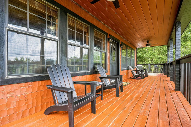 Step onto your private covered deck with warm wood tones and classic Adirondack seating—perfect for morning coffee while overlooking lush green surroundings.