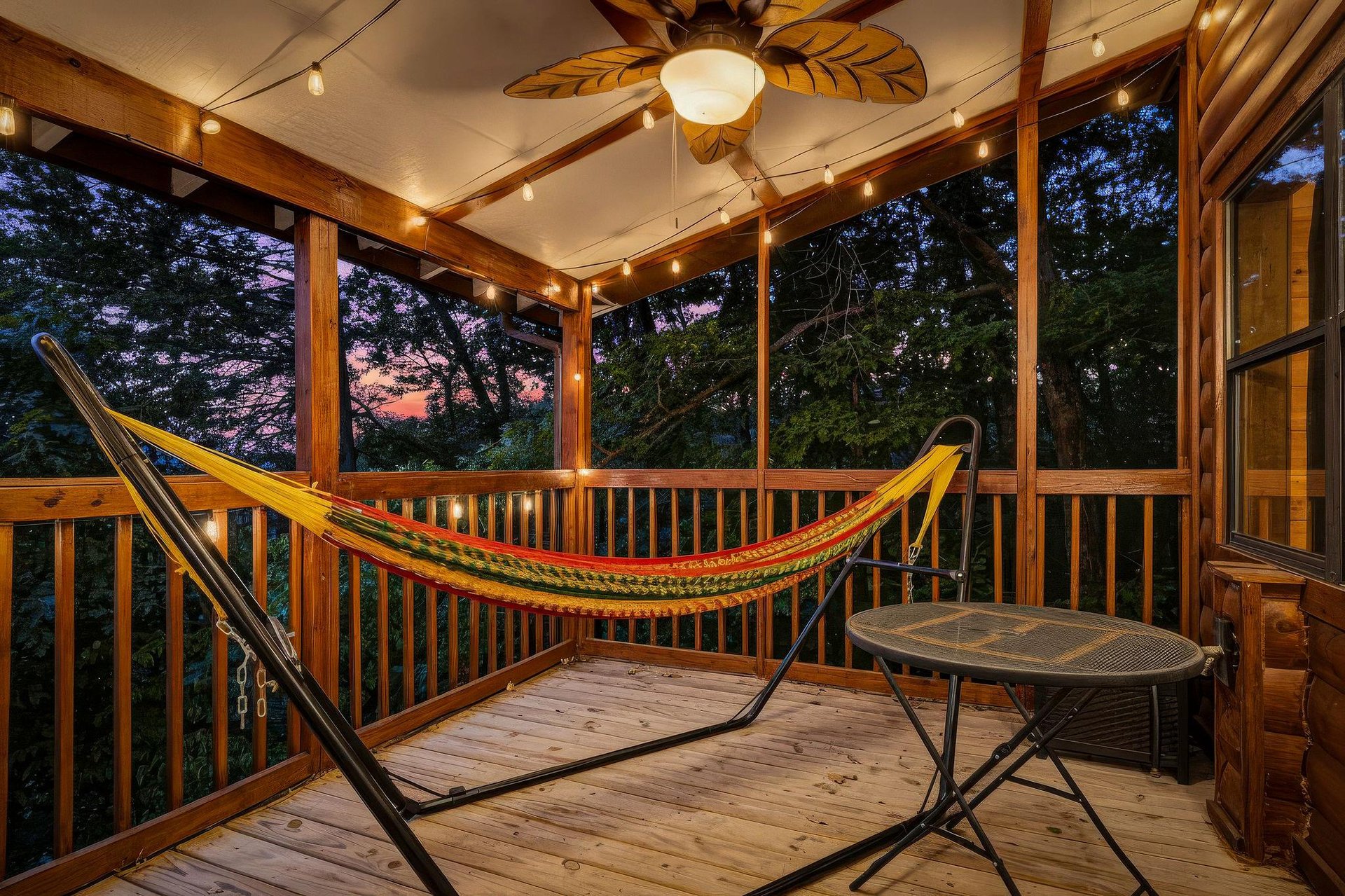 Sway into relaxation in your private screened porch. String lights and a ceiling fan create the perfect twilight ambiance while you gaze out at peaceful wooded surroundings.