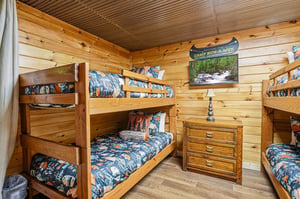 Step into your cozy retreat with warm woodpaneled walls and bunk beds dressed in playful campthemed bedding—perfect for restful nights after adventurous days.