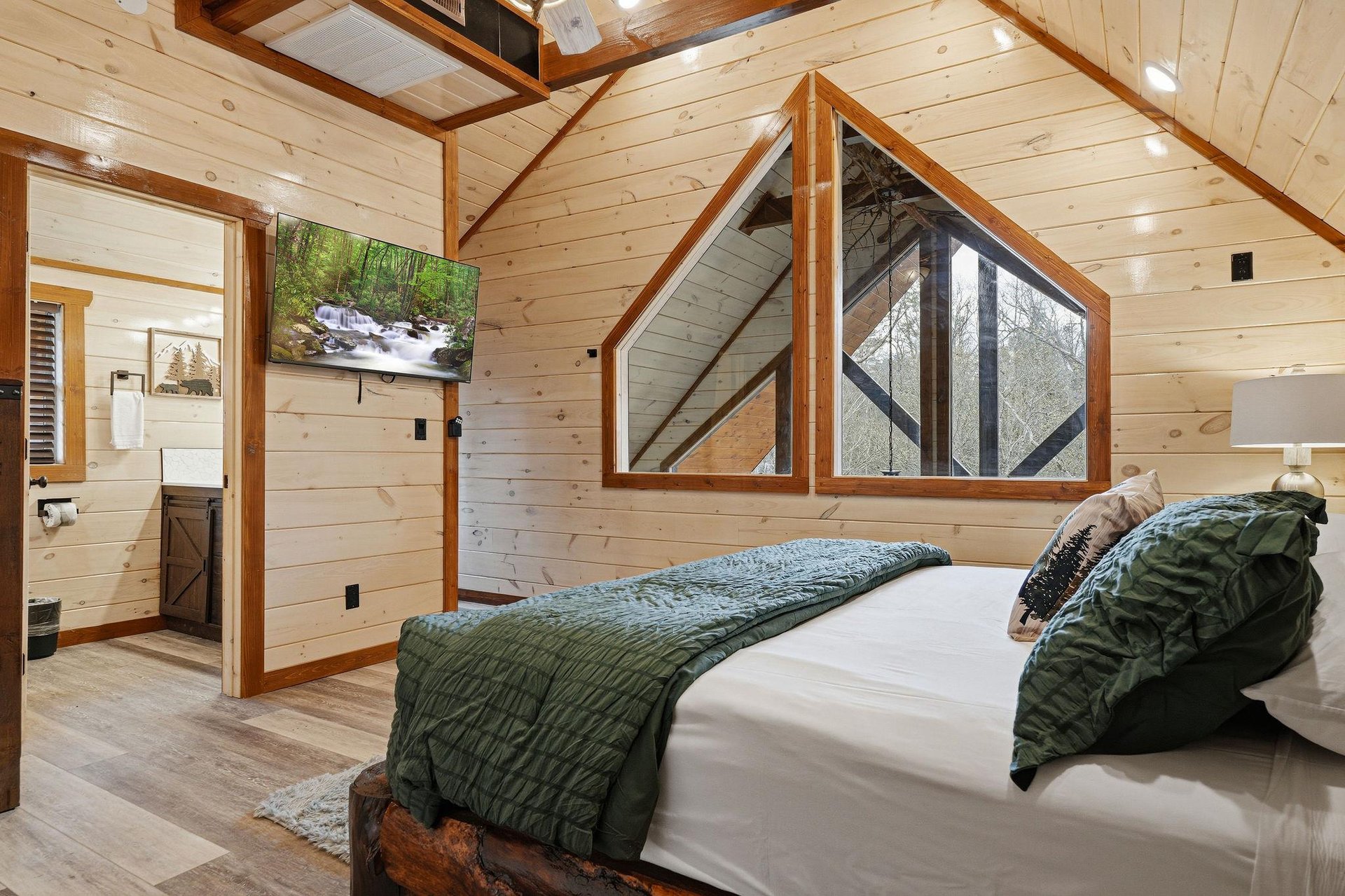 Drift off to sleep in your cozy loft bedroom, where warm wood beams frame treetop views and nature artwork creates perfect woodland serenity.