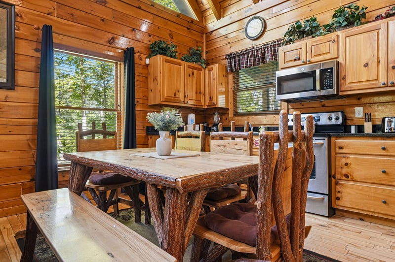 Gather around this handcrafted log dining table where rustic charm meets modern convenience. Your fullyequipped kitchen awaits with all the comforts of home, framed by warm wood and forest views.
