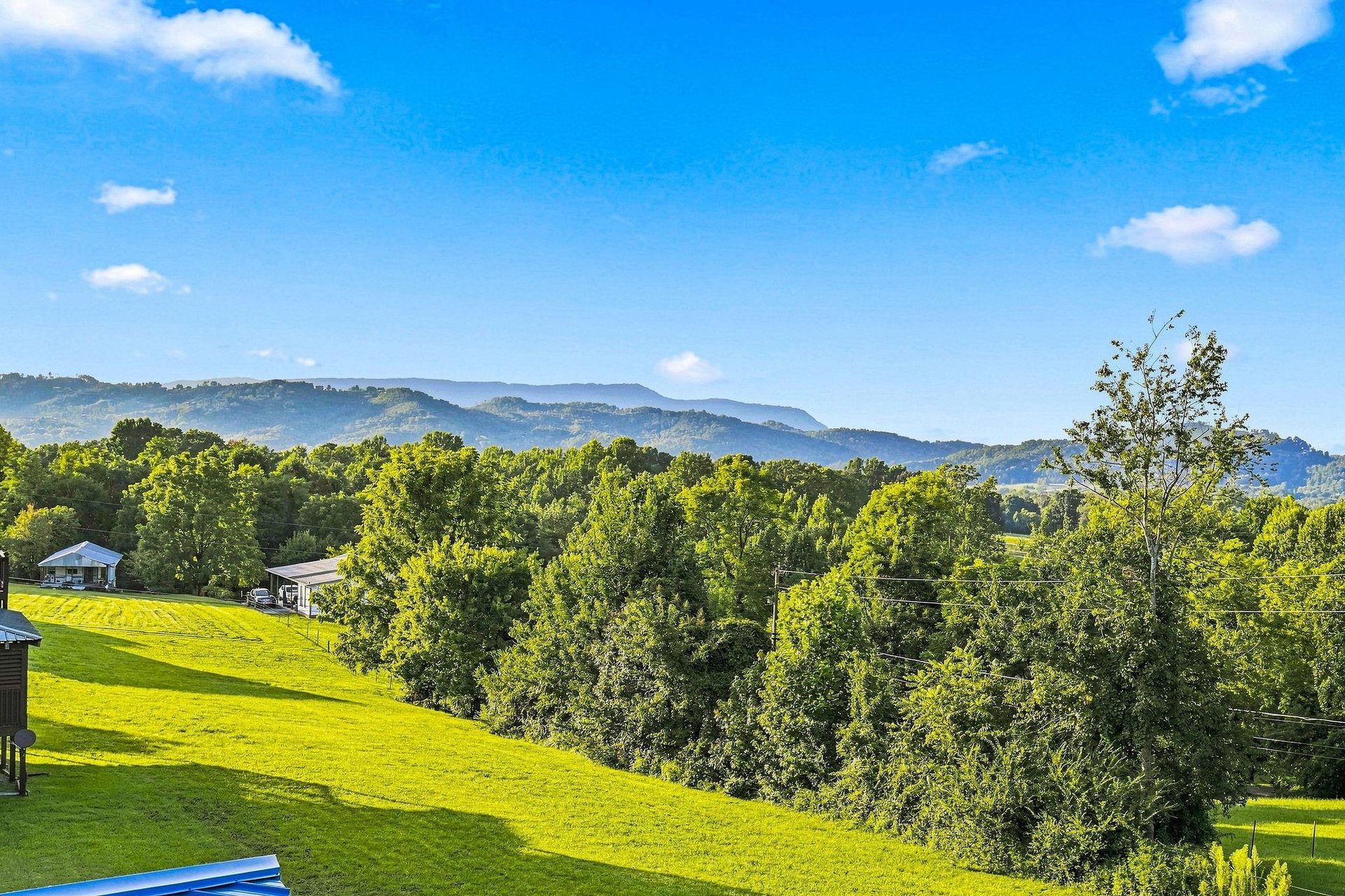 Stunning mountain vistas stretch across lush green landscapes, framed by trees and blue skies. The peaceful surroundings create an idyllic retreat setting.