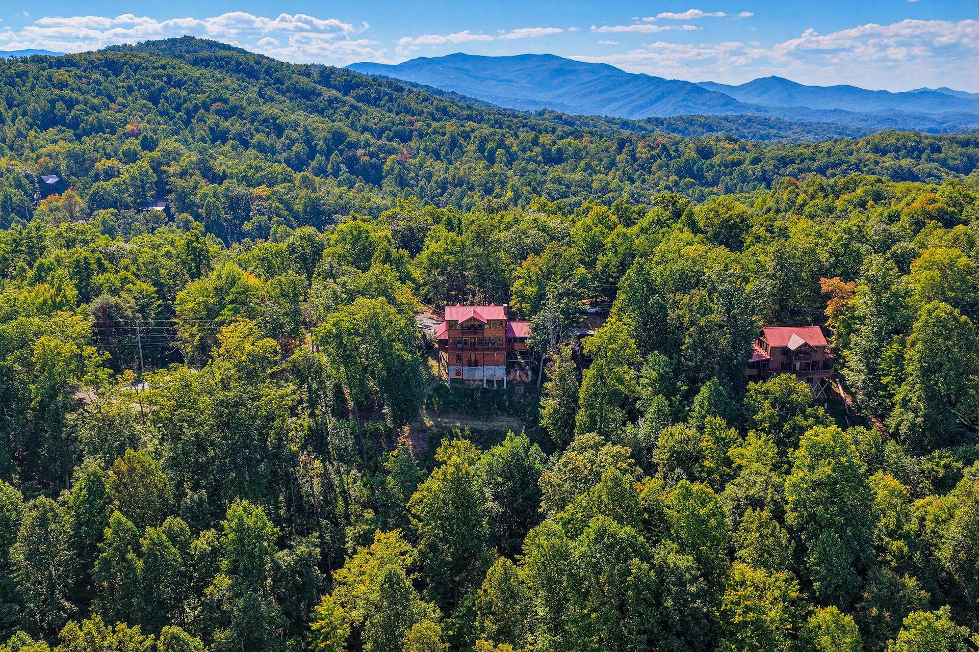 Aerial view of the property nestled in the Great Smoky Mountains, surrounded by lush forest canopy with sweeping mountain vistas stretching across the horizon.