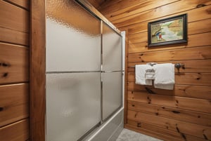 Step into your rustic bathroom with warm wood walls and a spacious glass shower where you can unwind after your mountain adventures.
