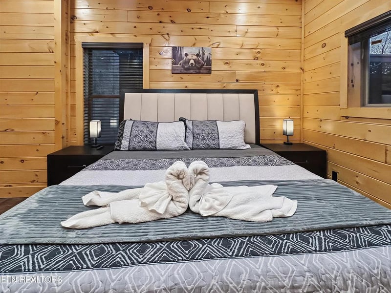 Unwind in your cozy cabin bedroom with elegant touches and a thoughtful towel swan display awaiting your arrival.