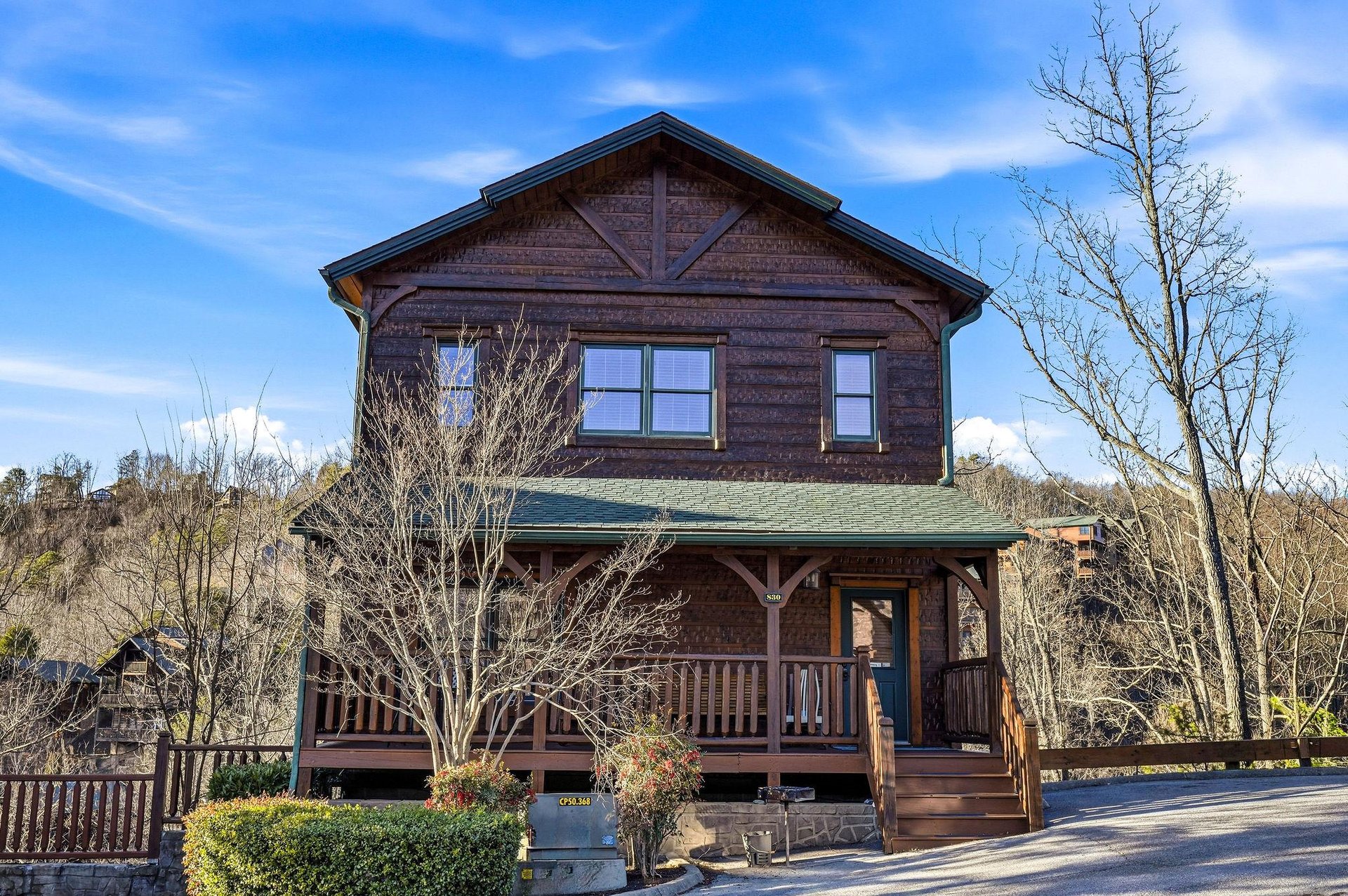 A charming rustic cabin with covered porch and mountain architecture provides a peaceful retreat in a scenic hillside setting.
