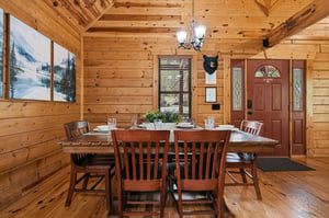 Gather around this inviting wooden dining table where warm cabin charm meets comfort for memorable meals with loved ones.