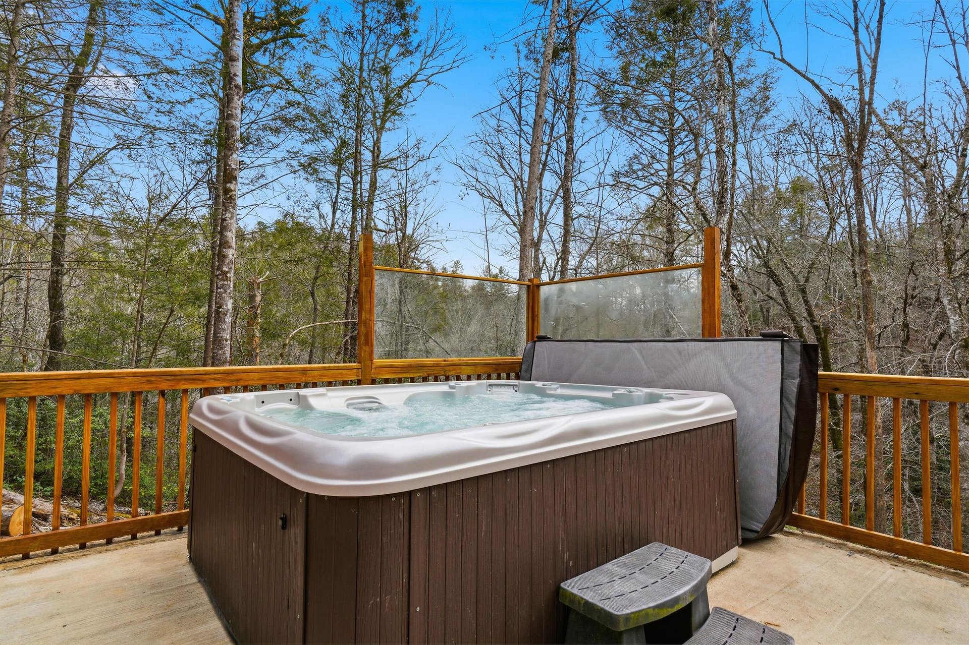 Soak in your private hot tub surrounded by towering trees and peaceful forest views on this secluded deck.