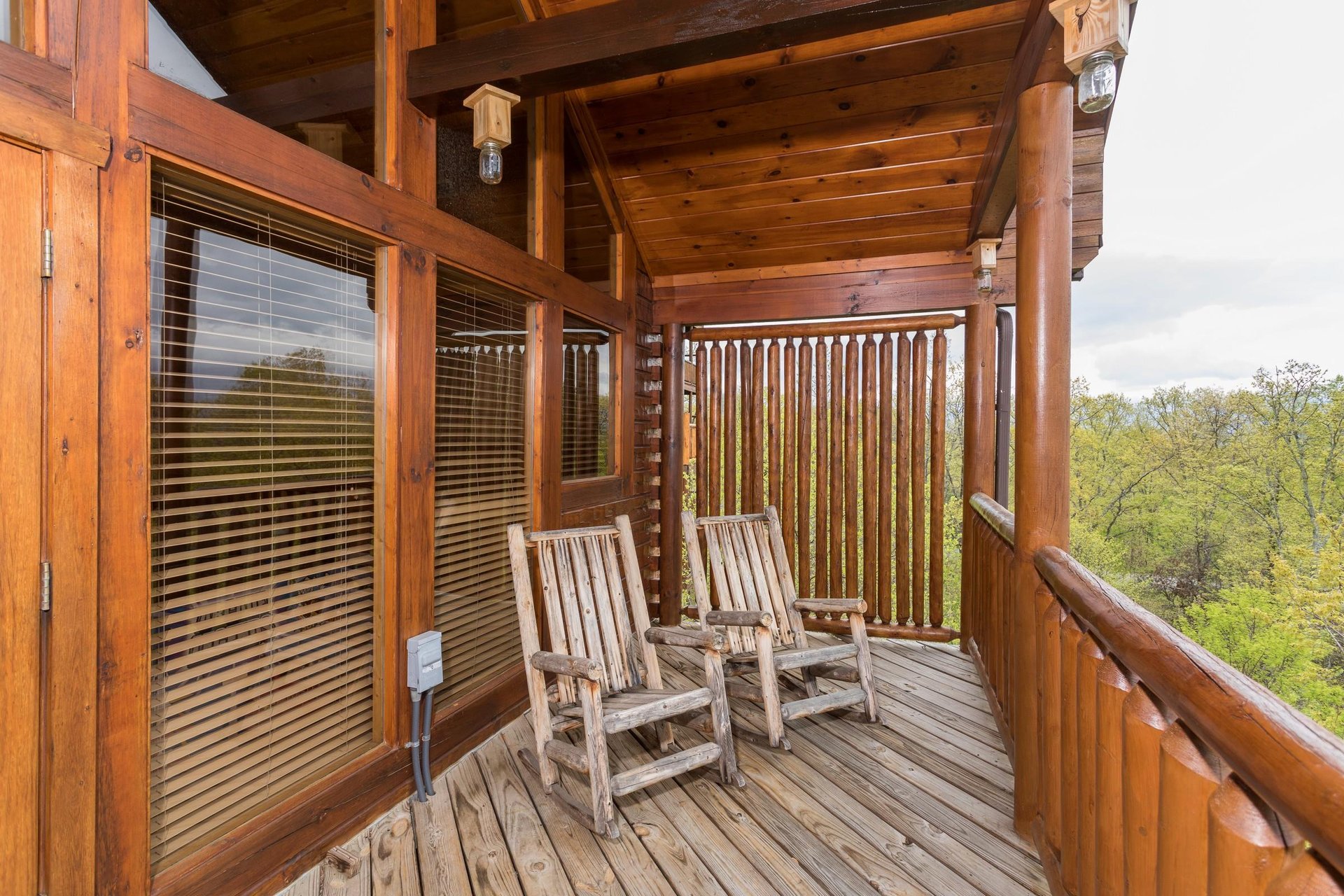 Covered deck with privacy fence and two rocking chairs at Howlin in the Smokies, a 2 bedroom cabin rental located in Pigeon Forge