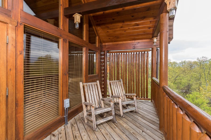 Covered deck with privacy fence and two rocking chairs at Howlin in the Smokies, a 2 bedroom cabin rental located in Pigeon Forge