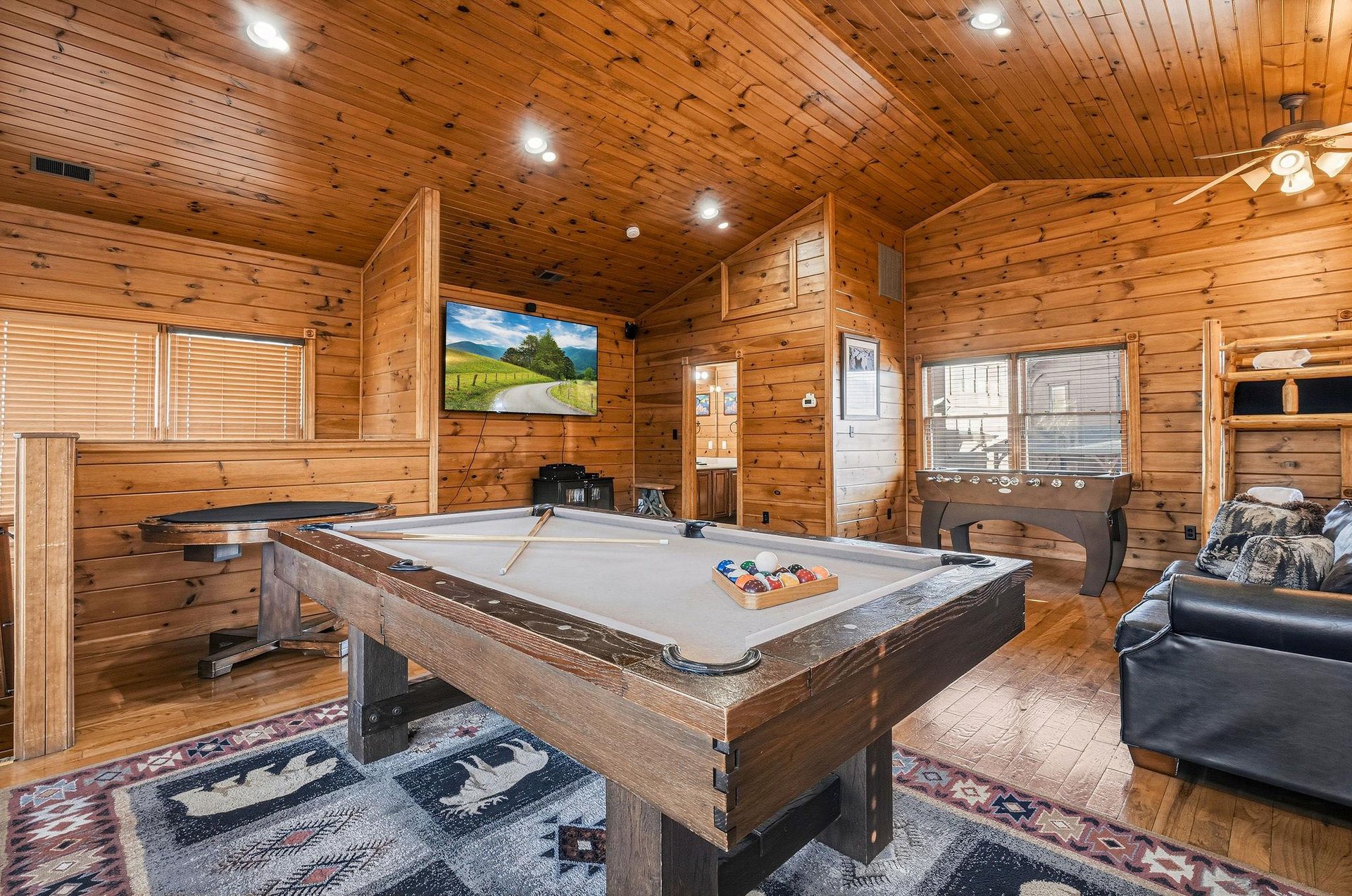 Gather your group for friendly competition in this rustic game room featuring a fullsize billiards table, cozy seating, and warm wood accents throughout.
