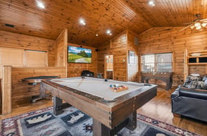 Gather your group for friendly competition in this rustic game room featuring a fullsize billiards table, cozy seating, and warm wood accents throughout.