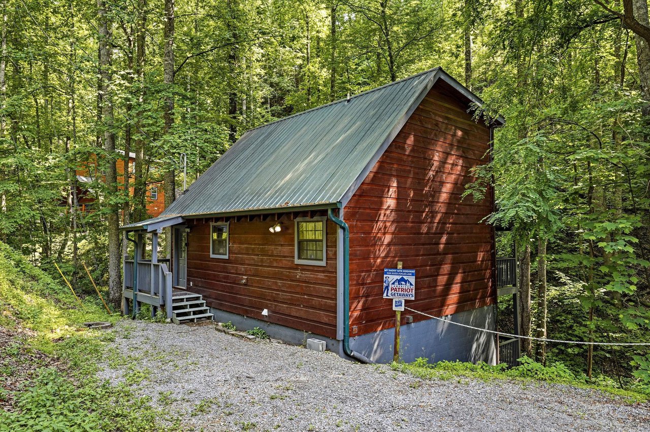 This charming cabin nestled in a lush forest offers a peaceful wooded retreat with convenient gravel parking at your doorstep.