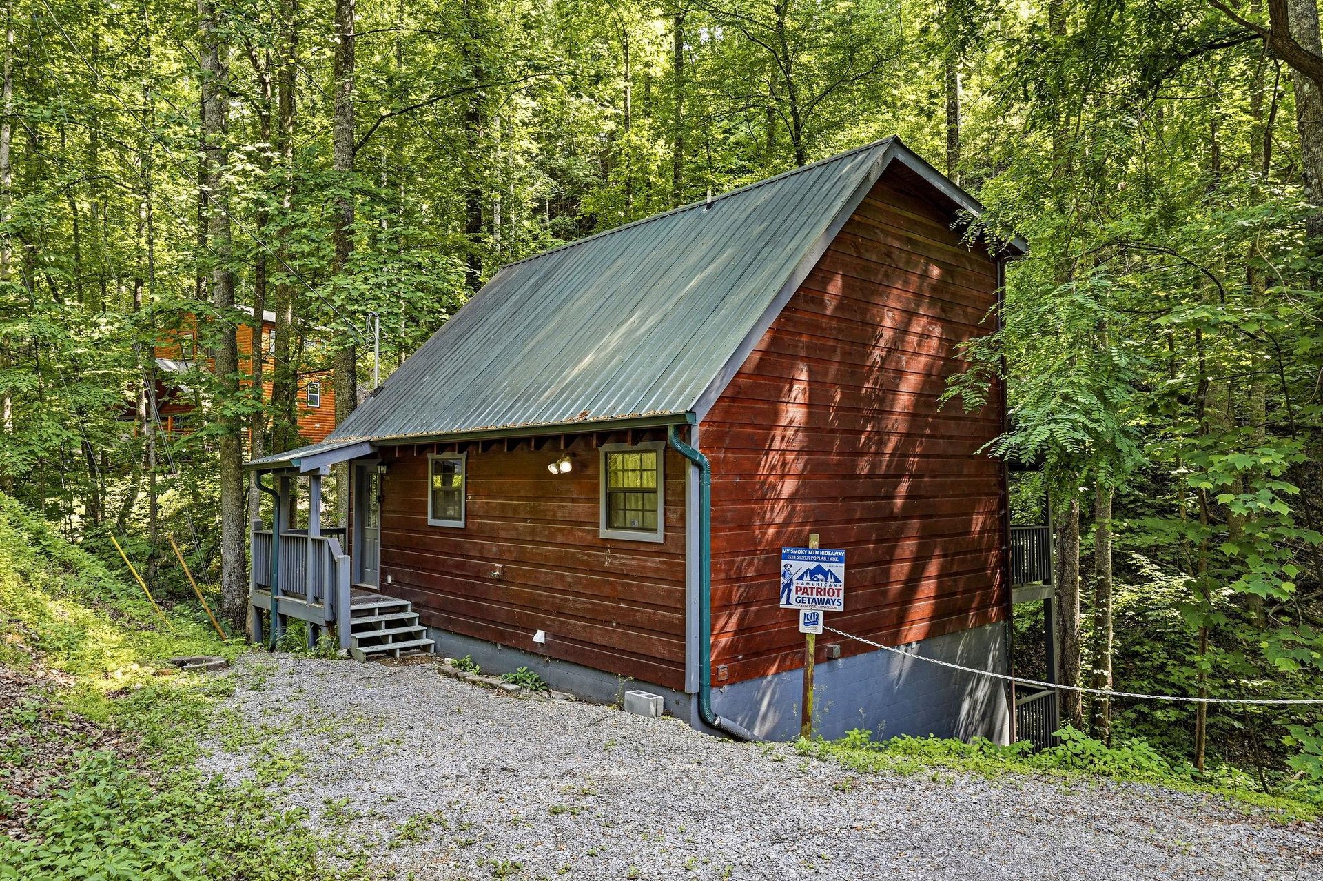 This charming cabin nestled in a lush forest offers a peaceful wooded retreat with convenient gravel parking at your doorstep.