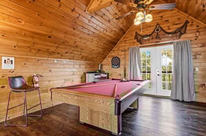 Challenge your friends to a game in this cozy log cabin game room, complete with vaulted ceilings and rustic charm.