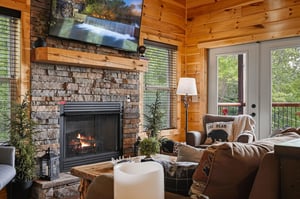 Sink into plush seating by the glowing stone fireplace, where warm wood surrounds you and treetop views await beyond your private balcony doors.