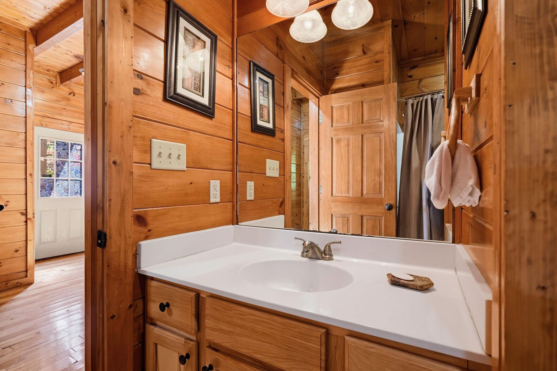 Unwind in your private bathroom with warm wood tones, a spacious vanity, and thoughtful cabin charm—perfect for freshening up after a day of adventure.