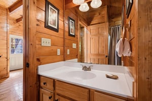 Unwind in your private bathroom with warm wood tones, a spacious vanity, and thoughtful cabin charm—perfect for freshening up after a day of adventure.