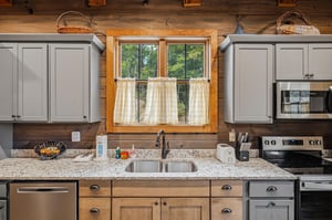 Your fullyequipped kitchen blends rustic charm with modern convenience—cook your favorite meals while gazing at the peaceful woods through charming café curtains.