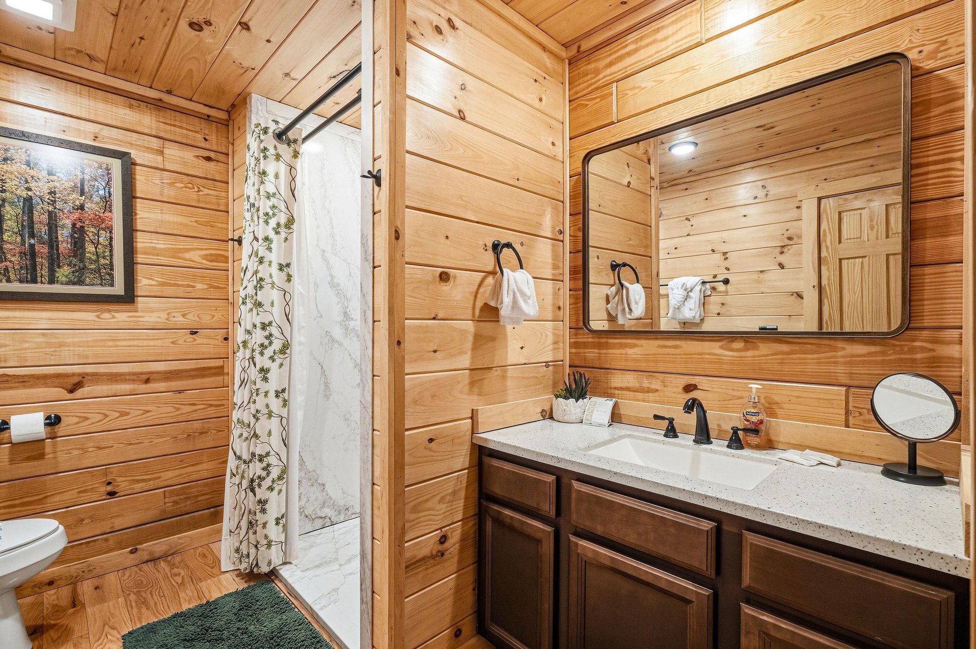 Step into your private rustic bathroom featuring beautiful wood paneling, granite countertops, and a spacious walkin shower.