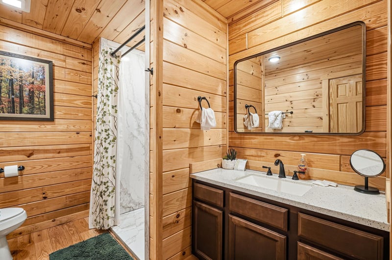 Step into your private rustic bathroom featuring beautiful wood paneling, granite countertops, and a spacious walkin shower.