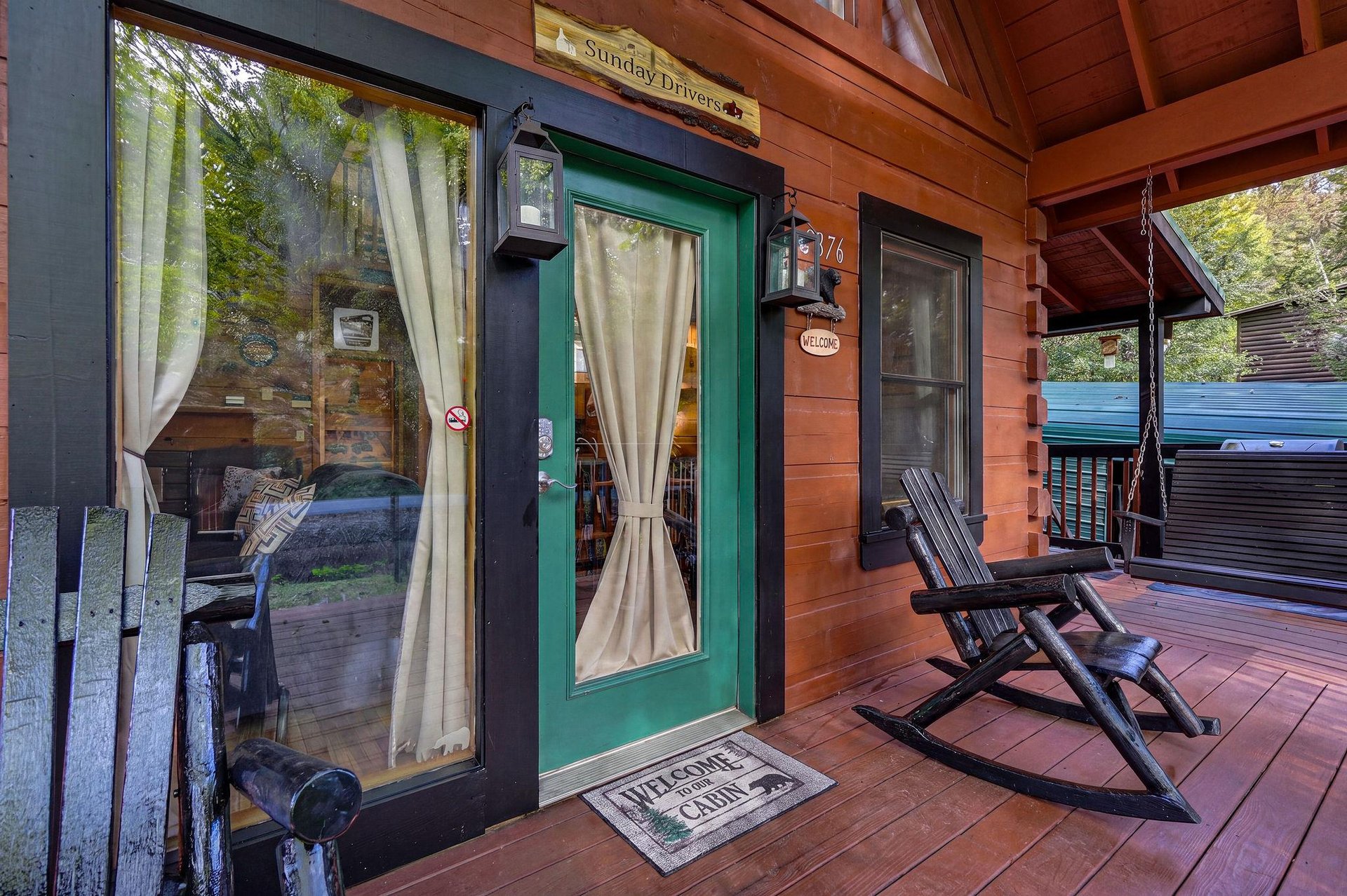 Step onto a welcoming front porch where a cozy rocking chair invites you to relax and enjoy the peaceful, treelined surroundings of your mountain cabin getaway.