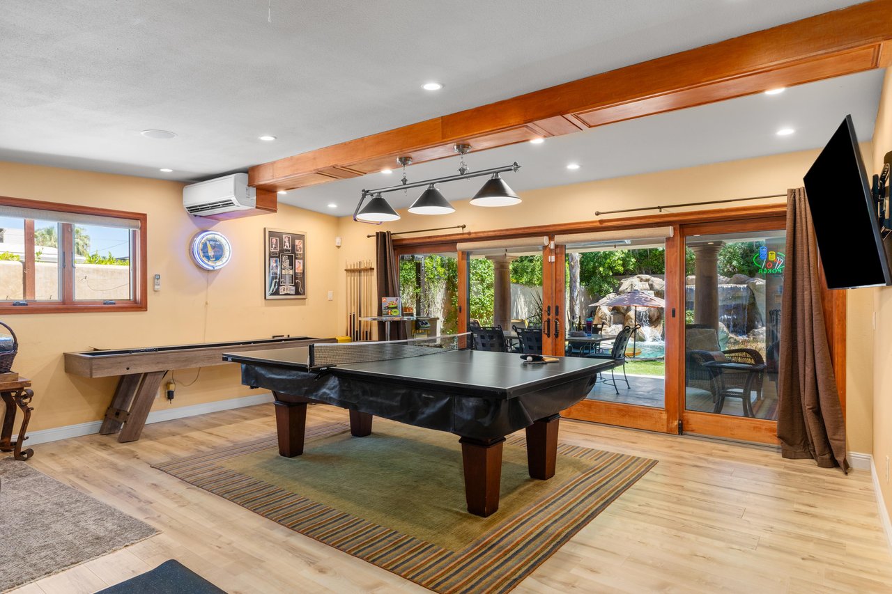 A game room with a private ping pong table, pool table, shuffle board, darts, arcade game, and flat screen TV.