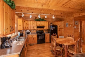Dining table for four in the kitchen with black appliances at Dreams Do Come True, a 1bedroom cabin rental located in Pigeon Forge
