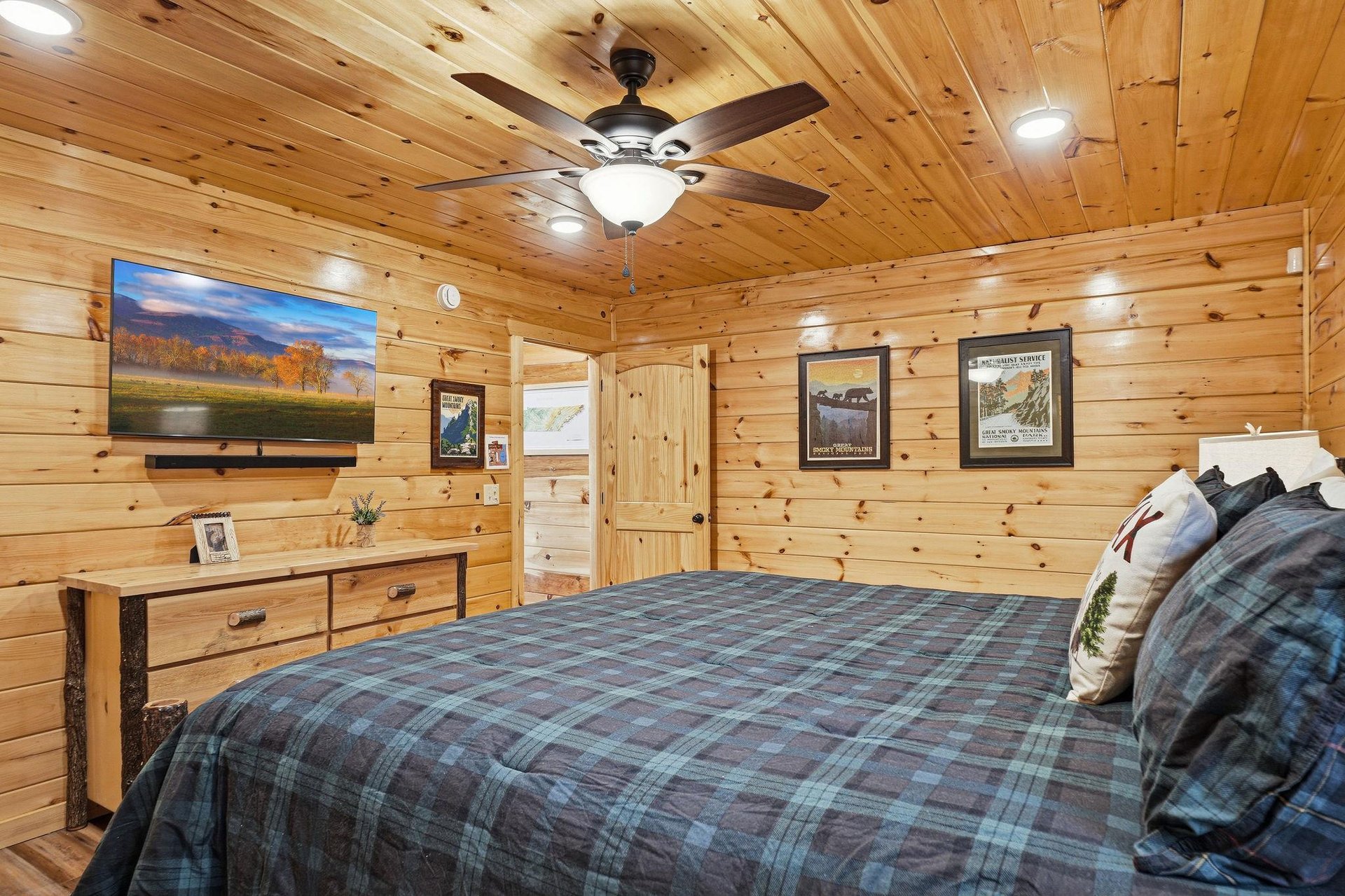 Drift off in your cozy log cabin bedroom, where rustic charm meets modern comfort with a ceiling fan and mountainthemed decor.