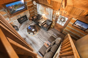 Take in the soaring vaulted ceilings and warm wood beams from this stunning loft view. Your cozy retreat features plush leather seating around a crackling stone fireplace, with windows framing mountai