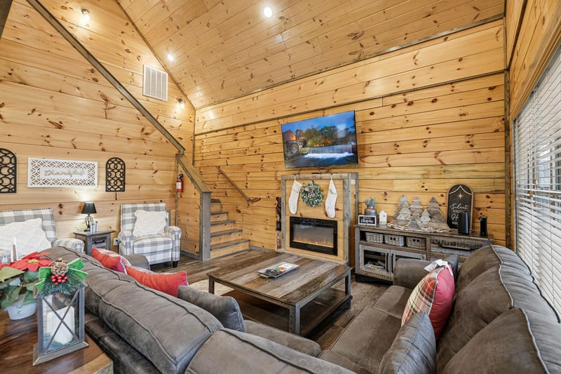 Cozy up in your rustic living room with plush seating, crackling fireplace, and warm wood walls for perfect mountain evenings.