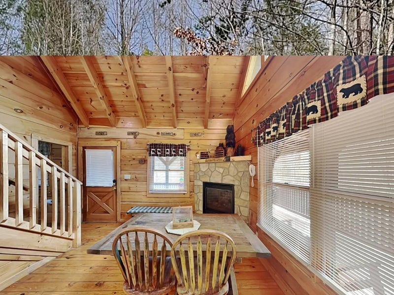 Gather around the rustic wooden table in this cozy cabin retreat, where warm pine walls and a stone fireplace create the perfect backdrop for your mountain getaway.